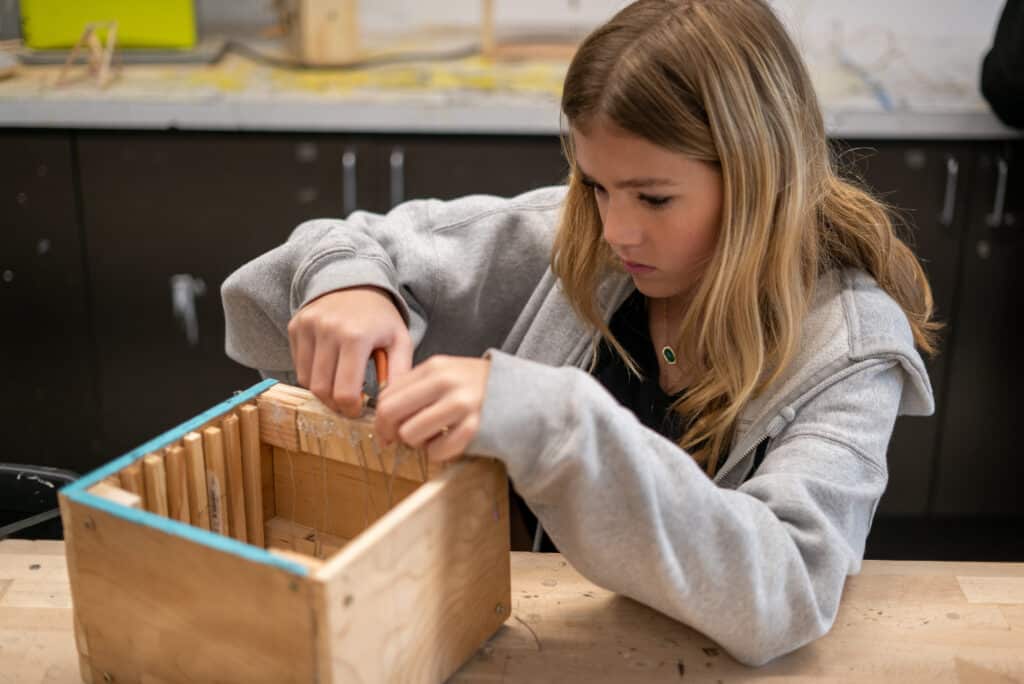 Students works on refinements to a wooden box.