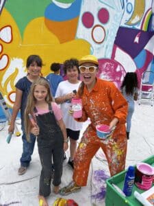 Muralist Scarlett Baily shares a moment with student helpers at High Tech Elementary Explorer.