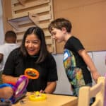 Interim CEO Diana Cornejo-Sanchez holds a magnifying glass in sharing a learning experience with TK students.