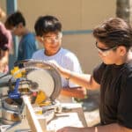 Two students work with tools to create a project together.
