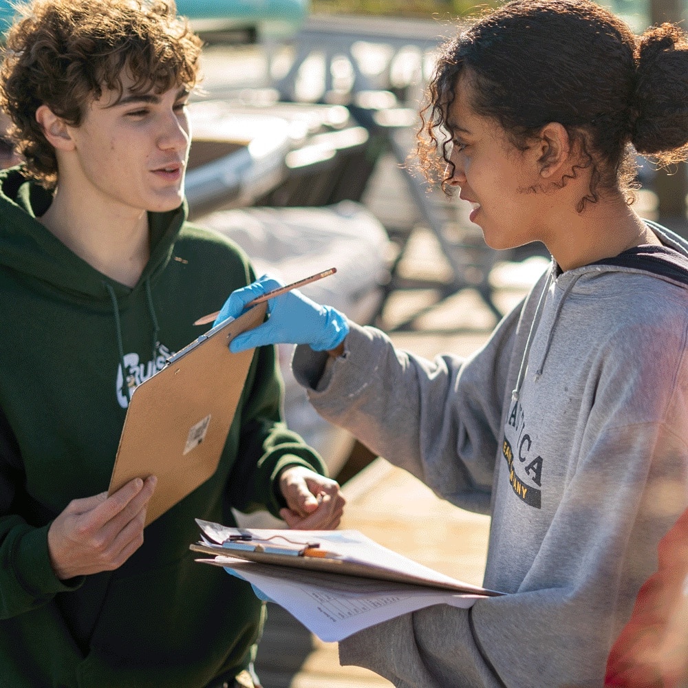 Two students review notes in outdoor setting.