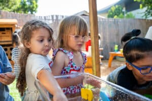 Two Transitional Kindergarten students play together outdoors.