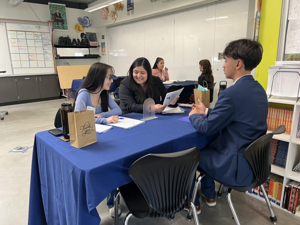 Student sits at a table with mentors as part of Internship Interview Day.