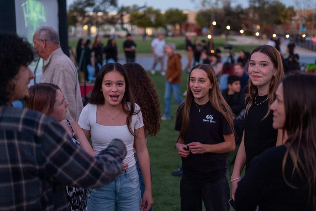 Students are at an evening exhibition together and smiling.
